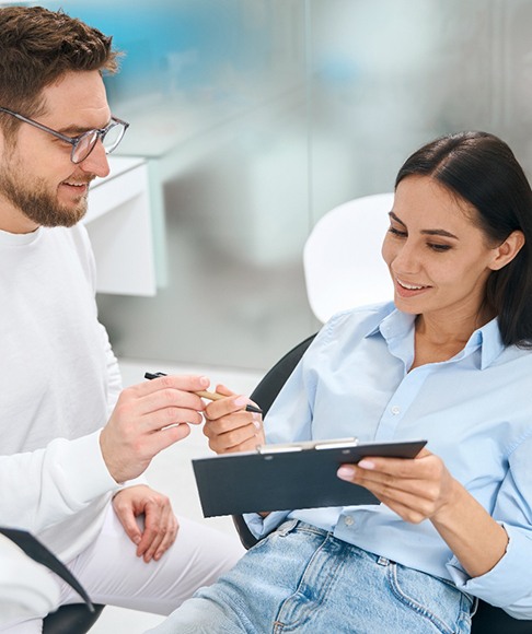 Dentist and patient talking while patient holds a clipboard