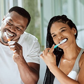 Couple brushing teeth in front of bathroom mirror