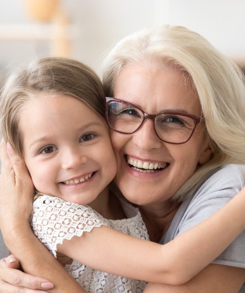 Older woman smiling with grandchild and enjoying the benefits of dental implants