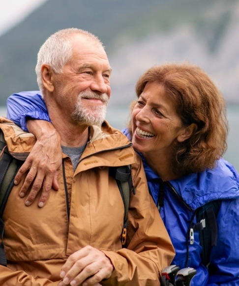 Older couple smiling after dental implant tooth replacement