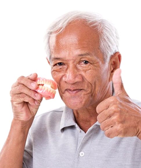 Man giving thumbs up holding dentures in Vero Beach