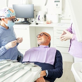 Senior patient conversing with his dental care team