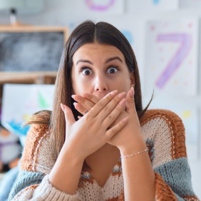 Woman with knocked out tooth covering mouth