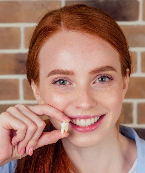 Woman holding up tooth after extraction