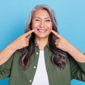 Happy mature woman pointing at her smile