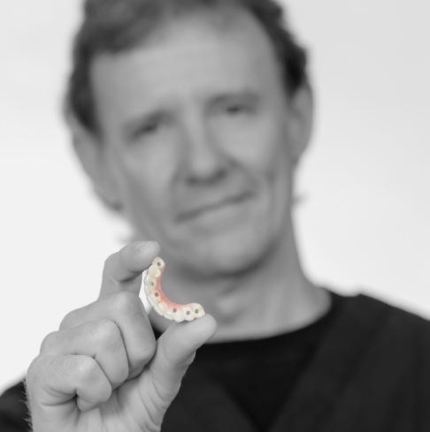 Man holding a dental restoration crafted in the on-site dental lab