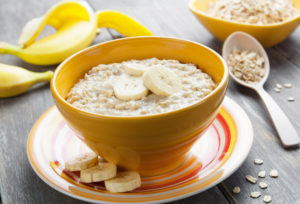 Oatmeal with bananas in a yellow bowl on the table