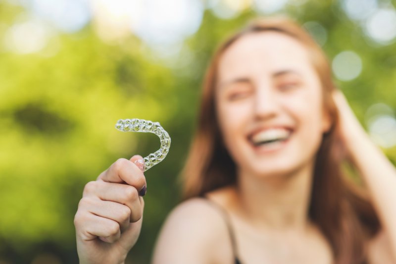 young woman holding a clear aligner