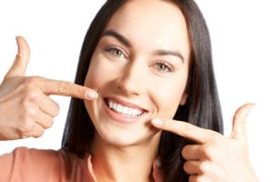 Woman with beautiful teeth pointing to her smile