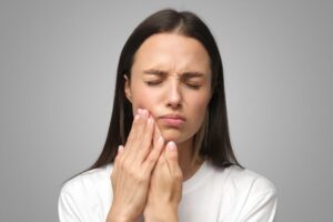 Woman in pain, touching one side of her jaw 