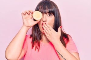Woman making surprised expression while holding a lemon 