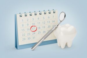 Tooth model and dental mirror next to calendar 